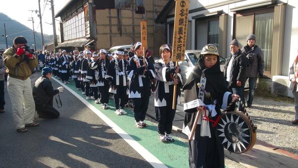 カメラで撮影している人の前を練り歩く子ども義士行列の写真